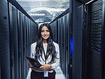 Mixed race technician holding digital tablet in server room