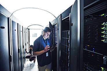 Technician using digital tablet in server room