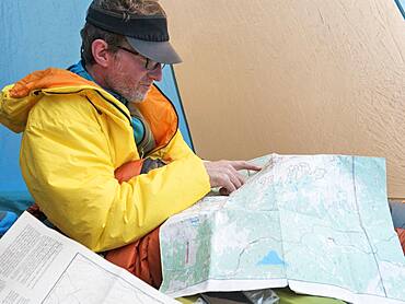 Caucasian man reading map in camping tent