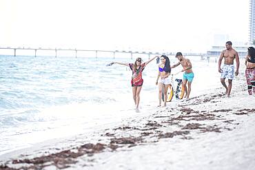 Friends walking in waves on beach