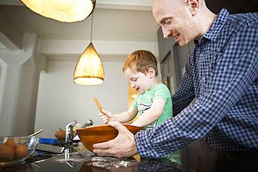 Father teaching son to cook in kitchen