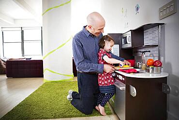 Father and daughter playing in toy kitchen