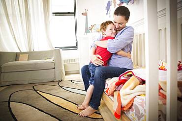 Mother and daughter hugging on bed