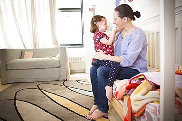 Mother and daughter sitting on bed