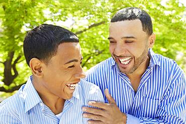 Hispanic father and son laughing in park