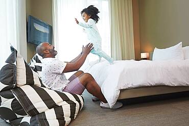 Black father and daughter playing in bedroom