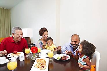 Multi-generation family eating breakfast at table