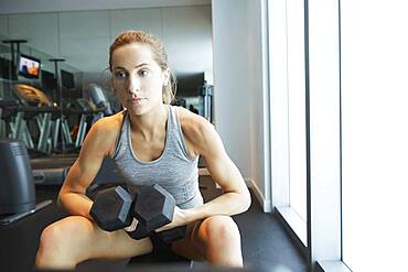 Serious woman lifting weights in gym