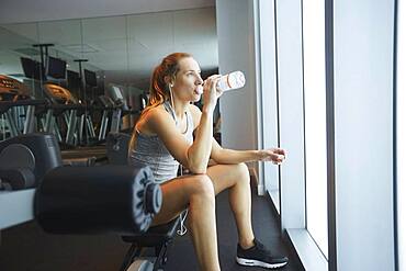 Woman drinking water bottle in gym