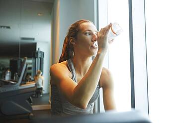 Woman drinking water bottle in gym