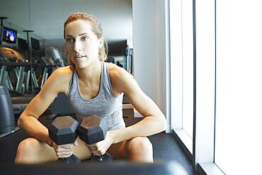 Serious woman lifting weights in gym