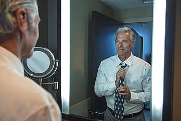 Caucasian businessman adjusting tie in mirror