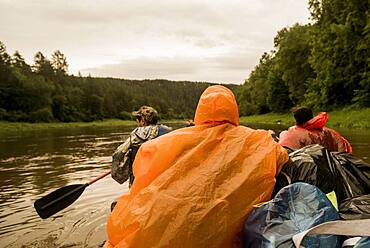 People wearing ponchos on boat in river