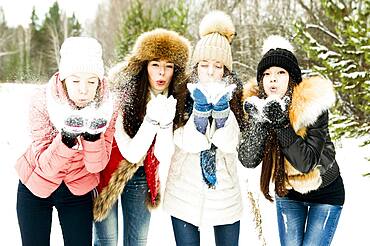 Caucasian girls blowing snow from hands