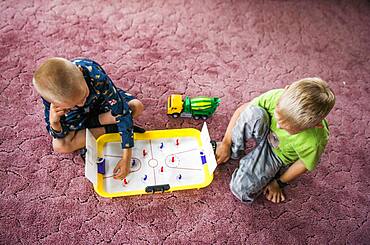 Caucasian brothers playing hockey game on floor