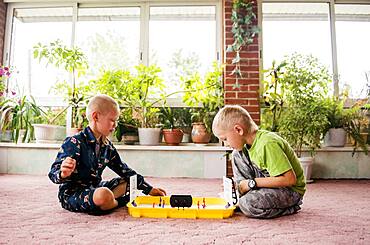 Caucasian brothers playing game on floor