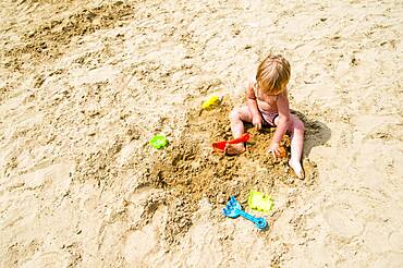 Caucasian girl playing in sand on beach