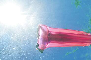 Underwater view of woman sunbathing on raft in ocean