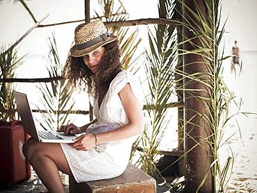 Woman using laptop in beach hut