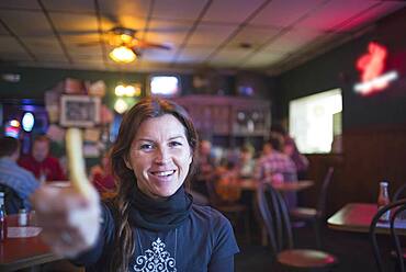 Caucasian woman offering french fry in bar