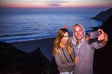 Caucasian couple taking selfie at beach