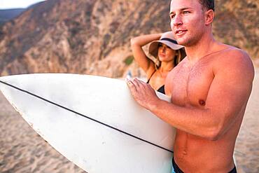 Caucasian surfer carrying surfboard on beach