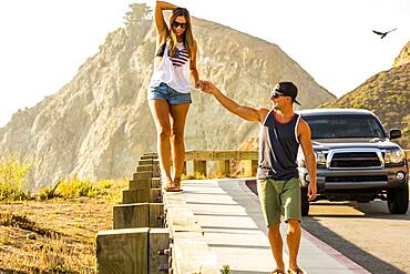 Caucasian man assisting woman walking on railing