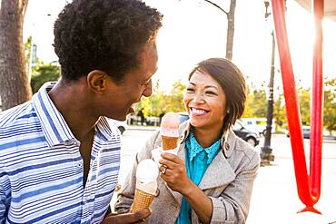 Smiling couple eating ice cream in park