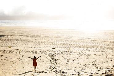 Caucasian girl standing with arms outstretched on beach