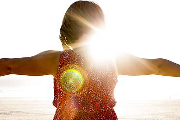 Caucasian girl standing with arms outstretched on beach