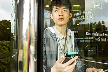 Asian man holding cell phone in doorway