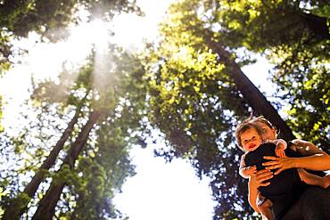 Caucasian mother holding baby girl under trees