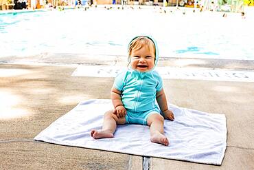 Caucasian baby girl sitting near swimming pool