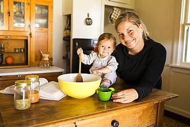 Caucasian mother and baby girl baking in kitchen