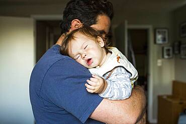 Caucasian father holding sleeping baby girl