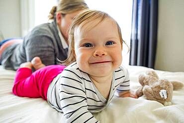 Caucasian mother and baby girl laying on bed