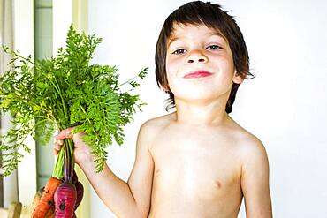 Mixed race boy holding fresh picked carrots