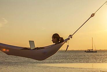 Caucasian woman using laptop in hammock