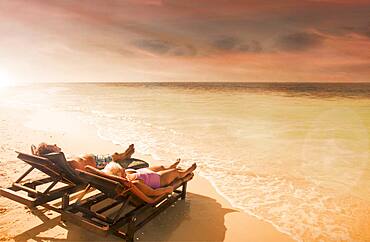 Older Caucasian couple relaxing on beach at sunset