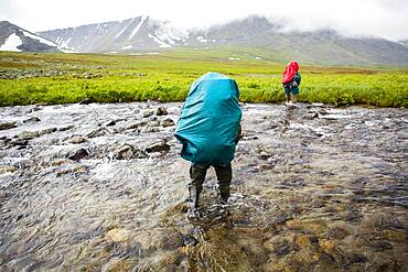 Backpackers crossing remote stream