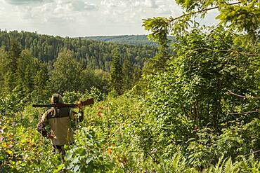 Mari man with gun overlooking rural landscape