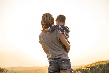 Mother holding son in rural field