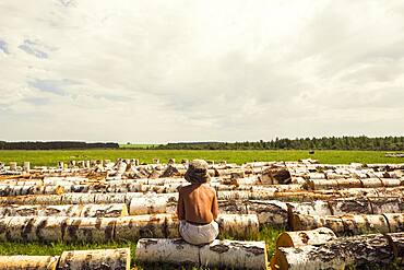 Mari boy sitting on log in rural field