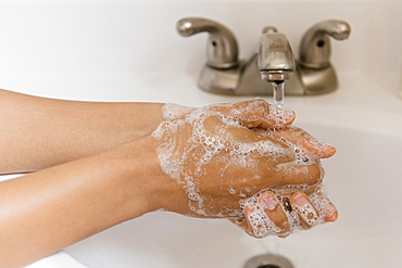 African American woman washing hands with soap