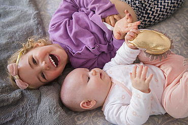 Caucasian girl laying on floor with baby sister