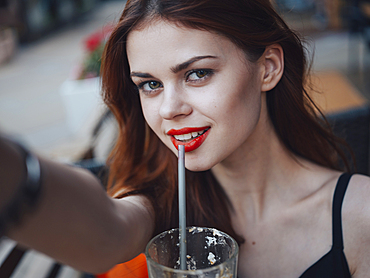 Smiling Caucasian woman drinking from straw posing for selfie