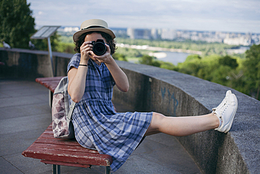 Caucasian woman sitting on bench photographing with camera