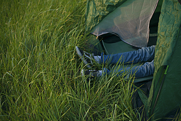 Legs of Caucasian man laying in tent