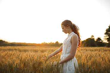 Caucasian girl standing in field of wheat