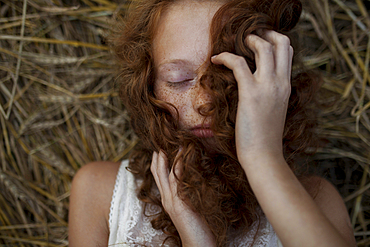 Caucasian girl laying in wheat holding hair